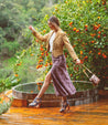 A woman walking on a Millennial deck with an orange tree in the background. Brand name: Bed Stu.