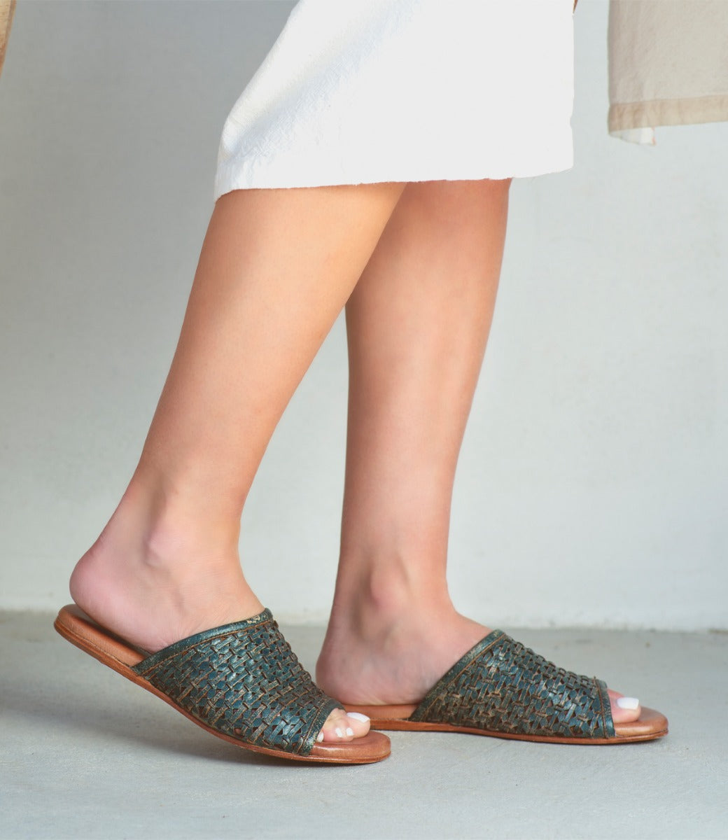 A woman's feet in a pair of Bed Stu Minerva woven sandals.