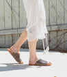A woman wearing a white dress and Bed Stu Minerva sandals.