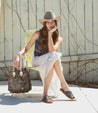 A woman in a Minerva cowboy hat sitting on a Bed Stu lawn chair.