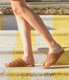 A woman wearing a pair of Bed Stu Minerva woven sandals on stairs.