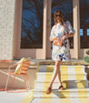 A woman wearing a pair of Bed Stu Minerva woven sandals on stairs.