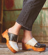 A woman wearing Bed Stu's eco-friendly black and white Mista clogs.