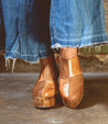 A woman wearing a pair of Bed Stu Mista sustainably sourced brown clogs.