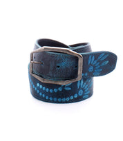 The Bed Stu Mohawk, a blue leather belt featuring an embroidered floral design and a silver rectangular buckle, is rolled up against a white background.