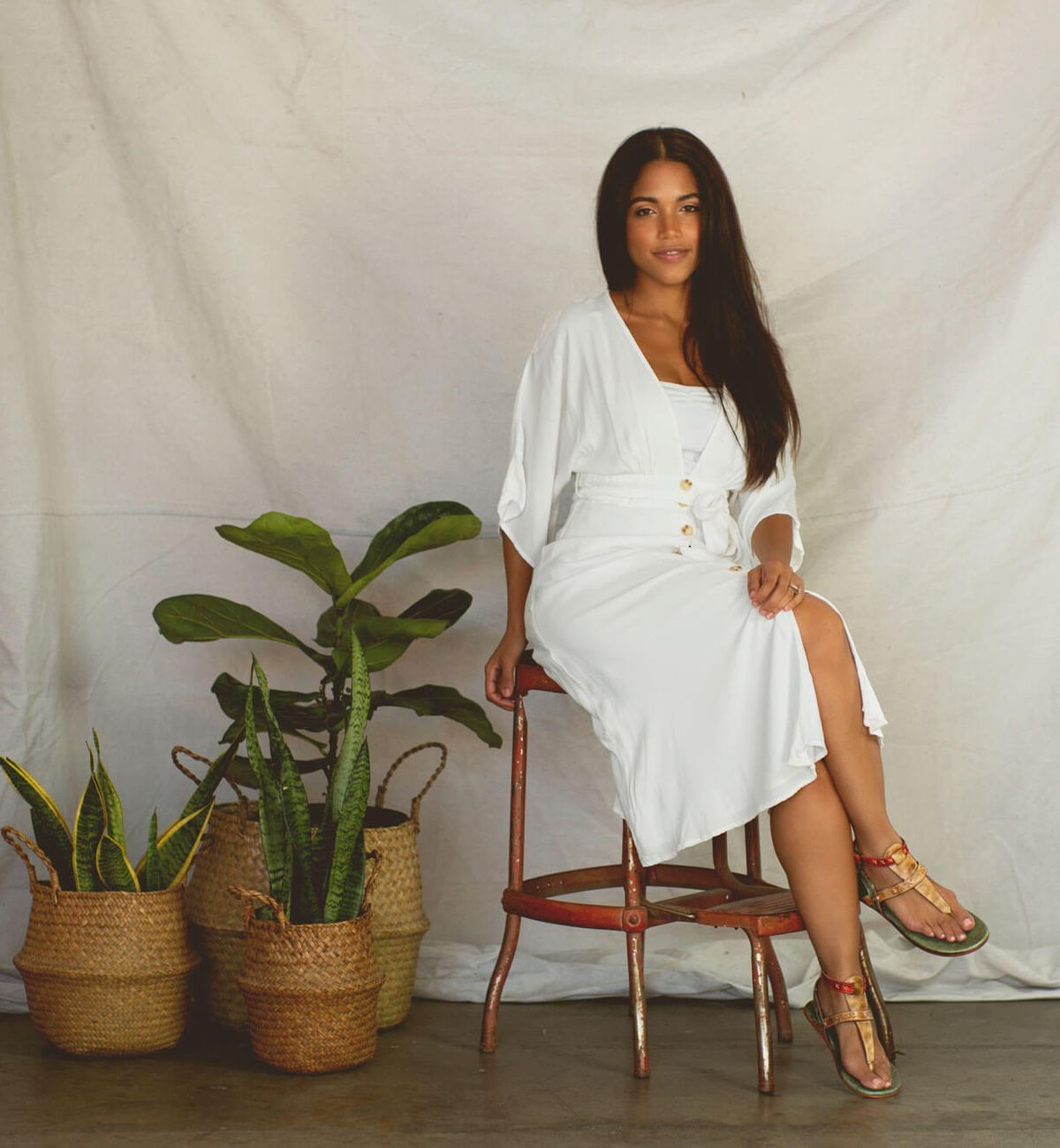 A woman in a white dress sitting on a Bed Stu Moon stool.