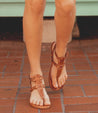 A woman wearing Bed Stu Moon sandals on a brick walkway.