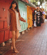 A woman in a tan dress walking down a sidewalk wearing Moon shoes by Bed Stu.