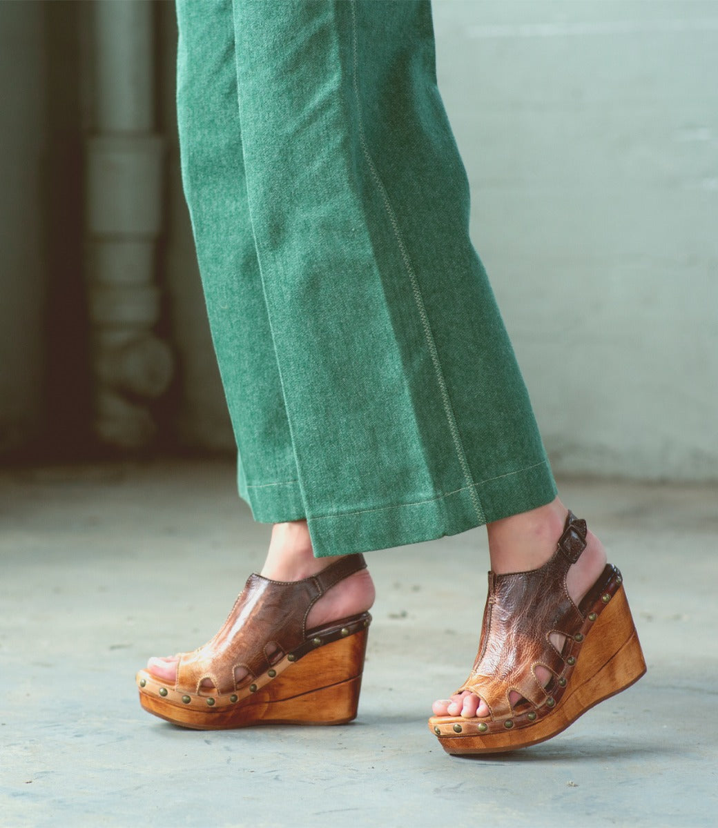 A woman wearing green pants and Bed Stu wooden wedges.