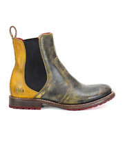 The Nandi by Bed Stu is a single leather Chelsea boot with a worn, vintage appearance, featuring elastic side panels and a pull tab at the back. This stylish piece of women's footwear showcases a brown and yellow color scheme with a striking red sole. Perfect for any woman looking to add fashionable boots to her collection.