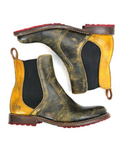 The Nandi women's boots by Bed Stu are distressed leather Chelsea boots in yellow and brown, featuring red soles and convenient pull loops, epitomizing fashion footwear.