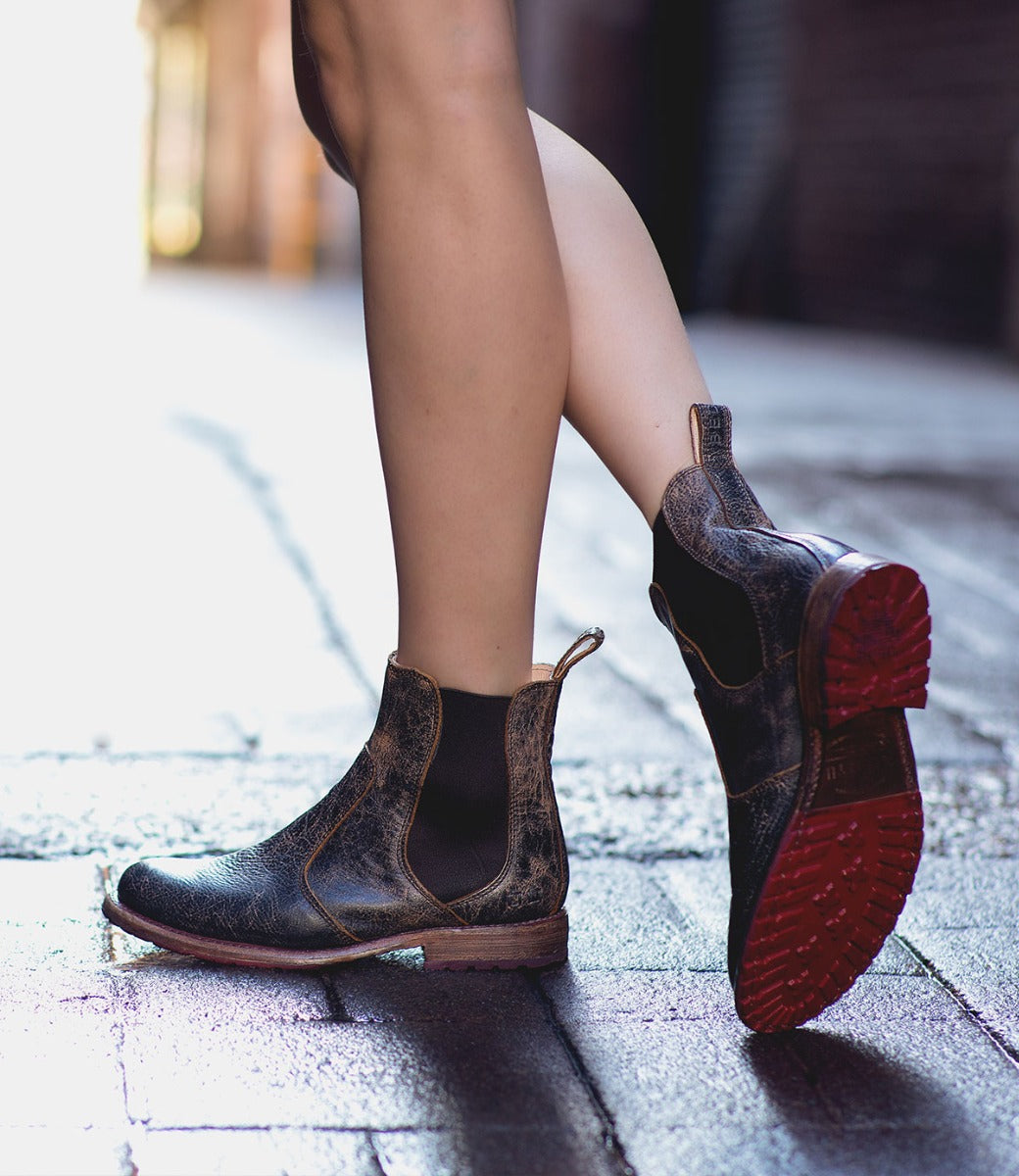 A woman wearing a pair of Bed Stu Chelsea boots on a sidewalk.