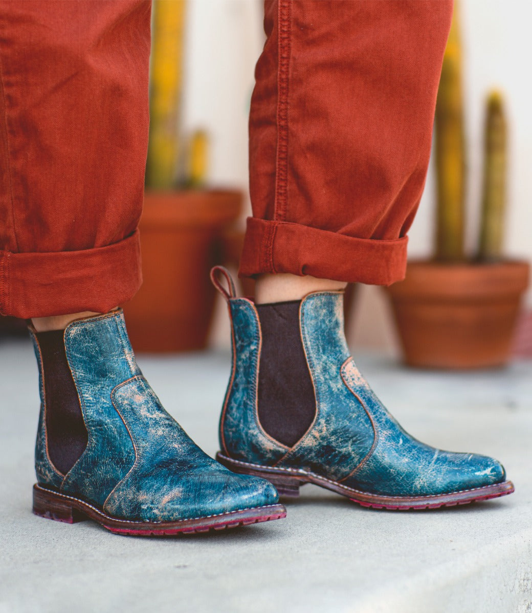 A person wearing Nandi leather boots in teal lux.