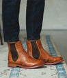 A person wearing Nandi pure leather chelsea boots in pecan color.