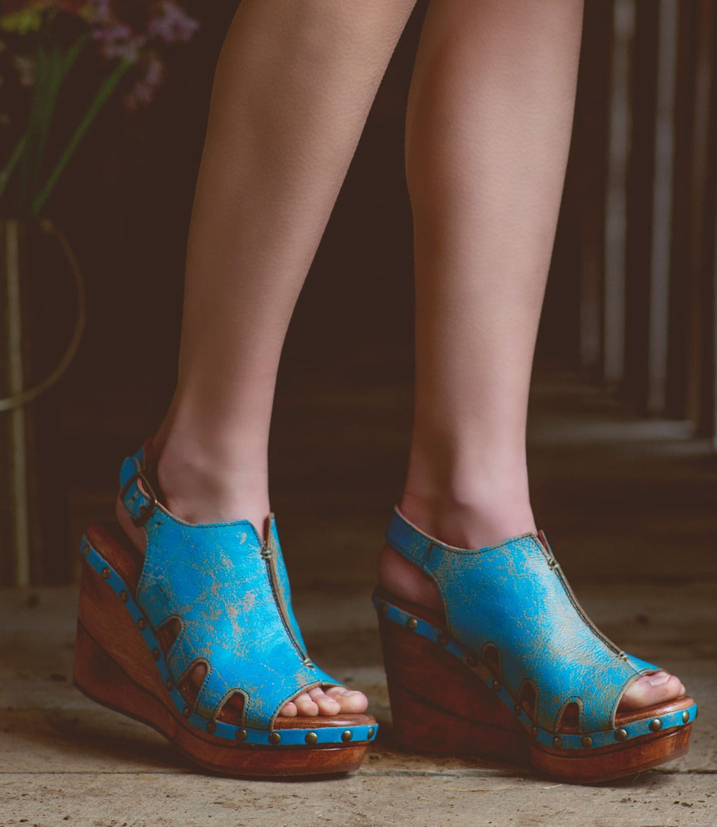 A woman's feet in blue Bed Stu Naiya wedge sandals.
