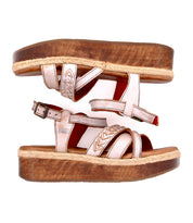 A pair of Bed Stu Necessary women's wooden flatform sandals with stitched straps and metallic braids are stacked sole to sole against a white background.