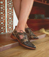 A woman's legs standing on a wooden floor in a pair of Neftis shoes by Bed Stu.