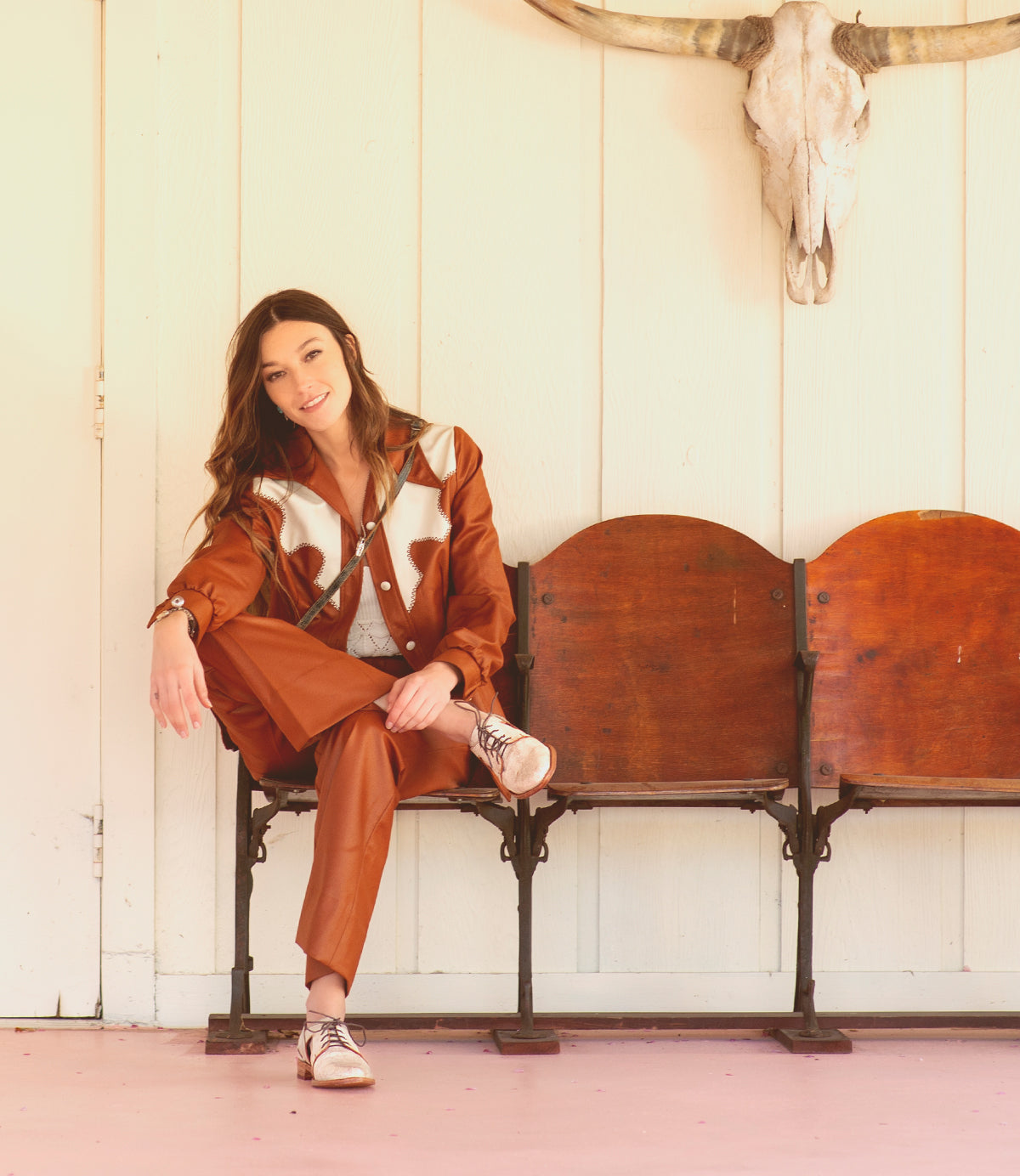 A woman sitting on a bench wearing a Bed Stu Neftis shoe.