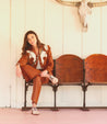 A woman sitting on a bench wearing a Bed Stu Neftis shoe.