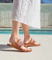 A woman wearing a white dress and Bed Stu sandals by a pool.