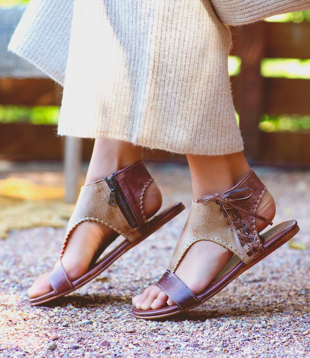 A woman's feet in a pair of Bed Stu brown sandals.