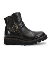 The Bed Stu Nudge II is a black leather ankle boot with a thick ridged sole, adjustable side buckle strap, and slight heel, displayed in left profile against a white background.