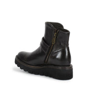 The Bed Stu Nudge II is a black leather ankle boot with a thick treaded sole, adjustable strap, and visible side zipper, displayed at an angle on a white background.