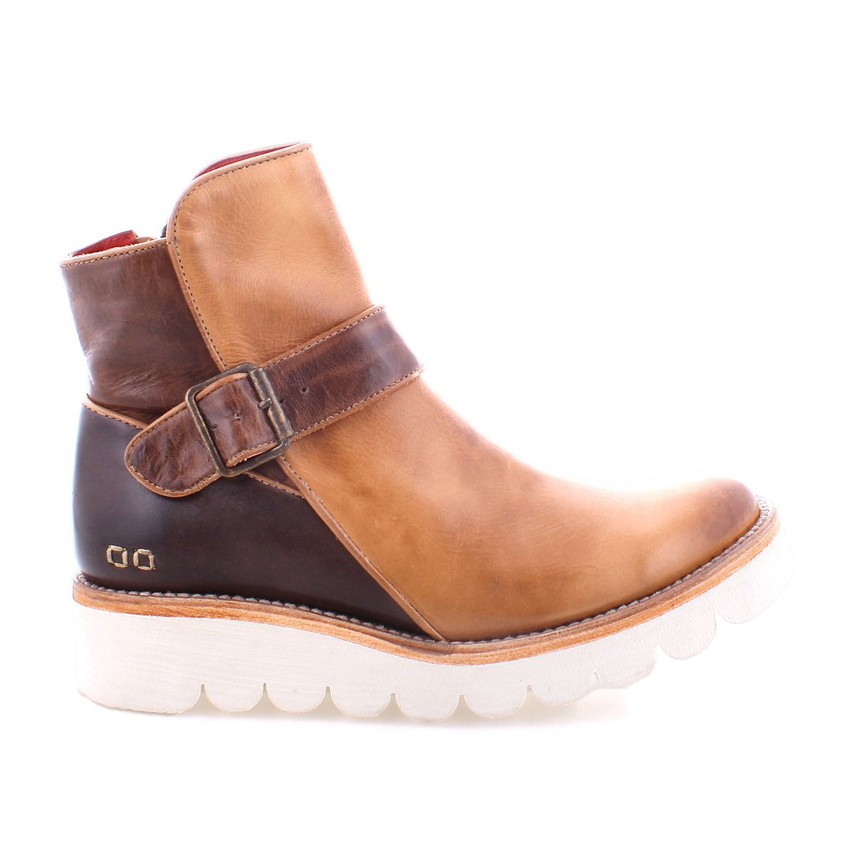 The Bed Stu Nudge II leather ankle boot, in tan and brown, features an adjustable buckle strap, white ridged sole, and convenient side zip, as seen from the side.