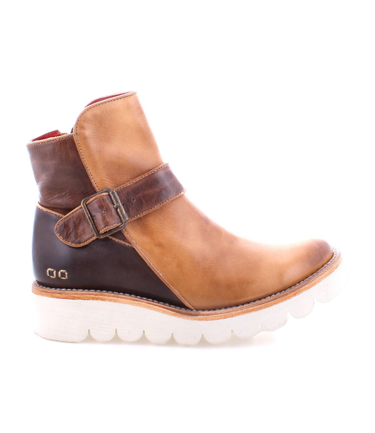 The Bed Stu Nudge II leather ankle boot, in tan and brown, features an adjustable buckle strap, white ridged sole, and convenient side zip, as seen from the side.