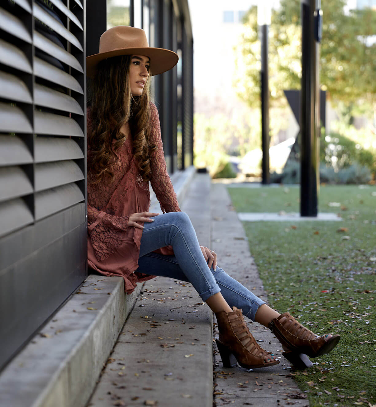 A woman wearing Occam P shoes by Bed Stu and jeans sitting on a wall.