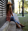 A woman wearing Occam P shoes by Bed Stu and jeans sitting on a wall.