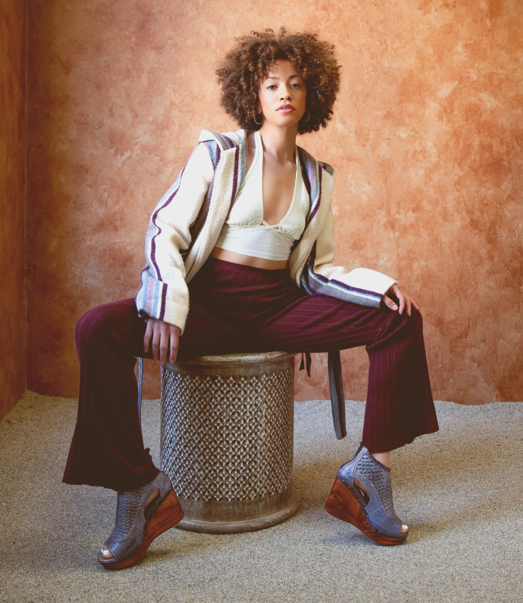 A woman sitting on a stool in an Odette jacket and Odette pants by Bed Stu.