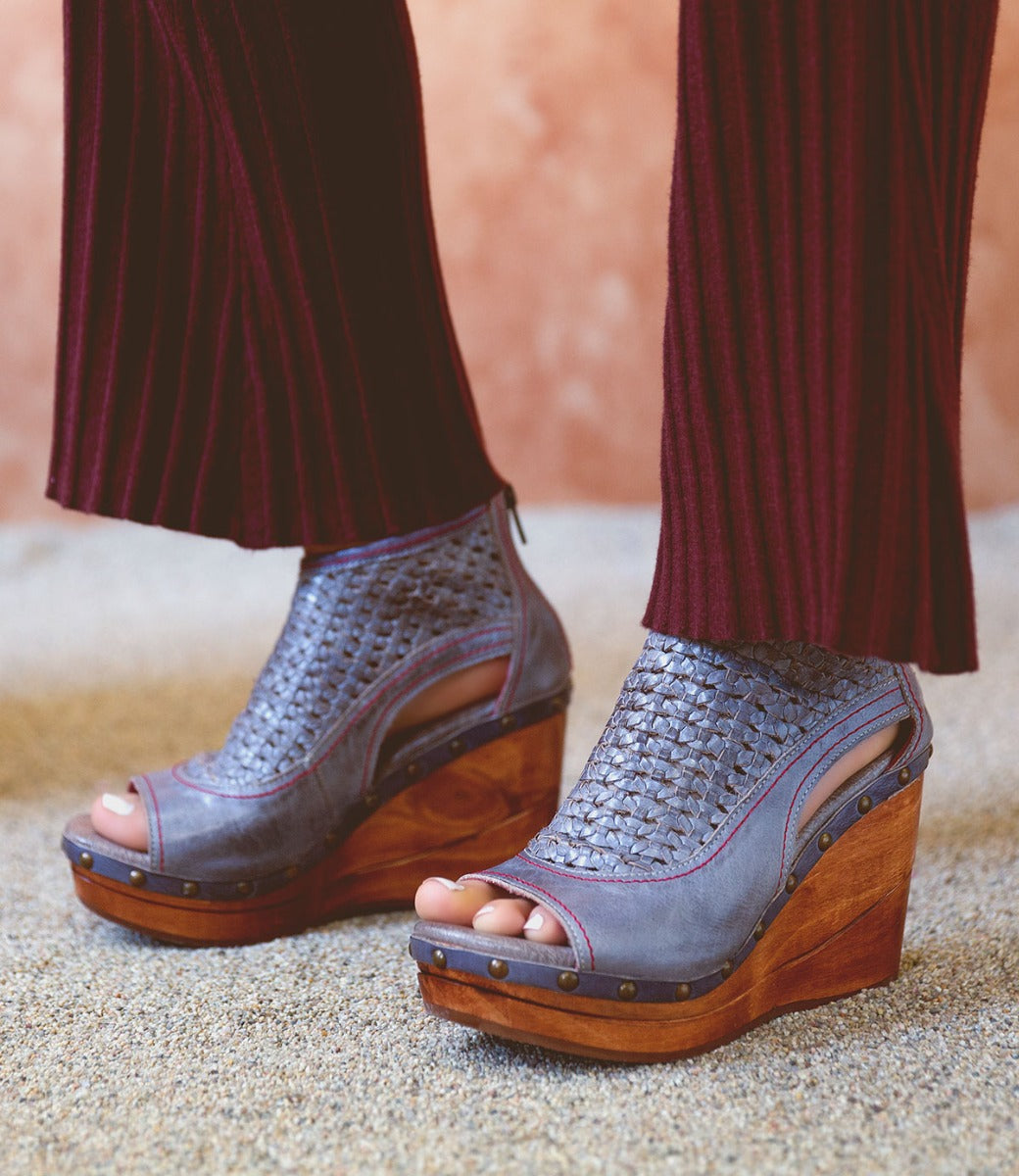 A woman's feet in a pair of Bed Stu Odette wedge sandals.