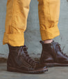 A person wearing a pair of Old Bowen Trek boots by Bed Stu and yellow pants.