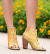 A woman wearing a pair of yellow Onset peep toe heels by Bed Stu.