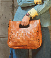 A woman is holding an adjustable handwoven Orchid handbag by Bed Stu.
