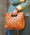A woman is holding an adjustable handwoven Orchid handbag by Bed Stu.