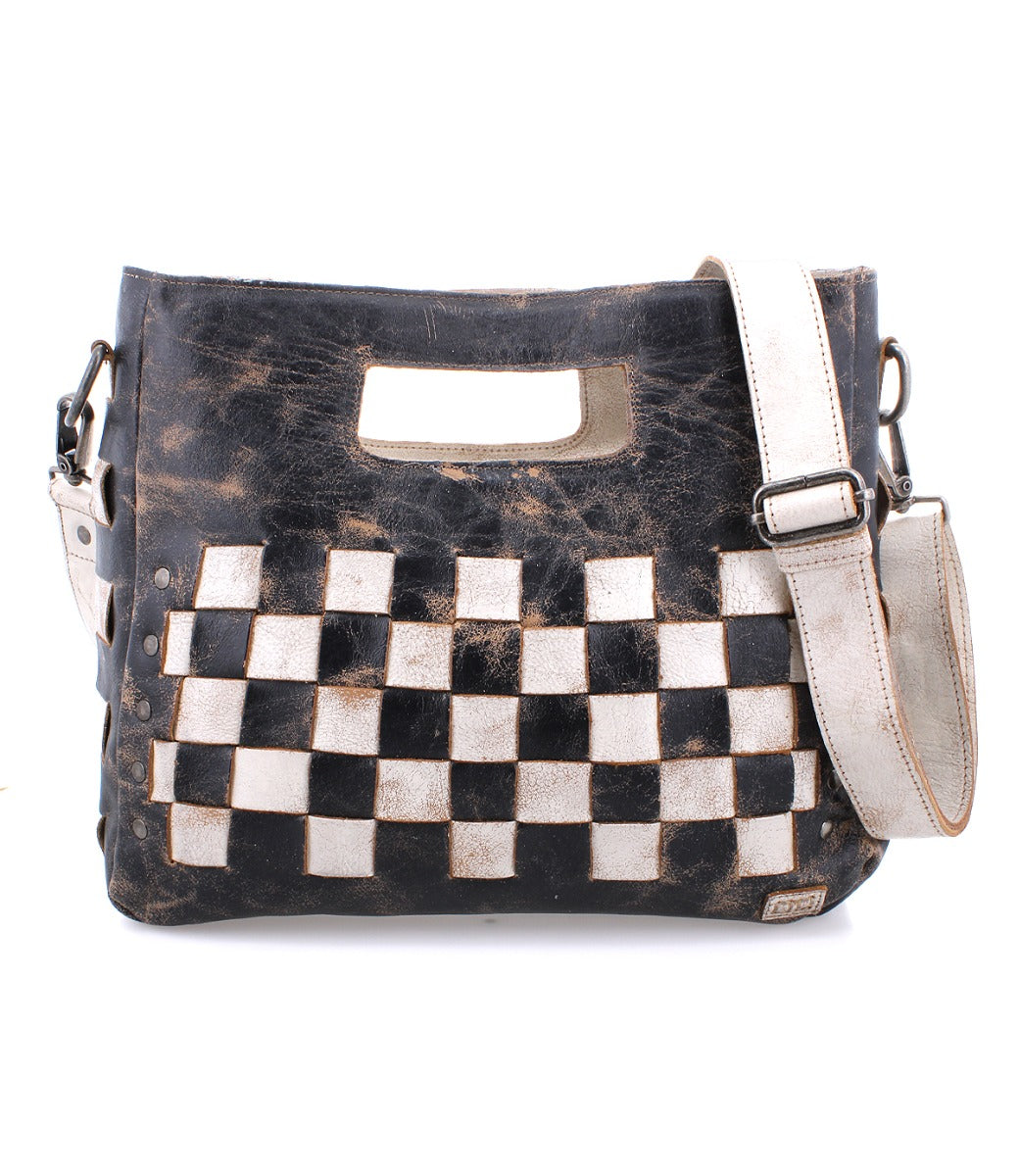 The Orchid shoulder bag by Bed|Stü features a modern, timeless design with its distressed, handwoven leather in a checkerboard black and white pattern. This stylish accessory offers a rectangular cutout handle, an adjustable strap, and is accented with an antique metal buckle for added flair.