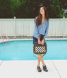 A woman standing next to a pool with a black and white Bed Stu Orchid bag.