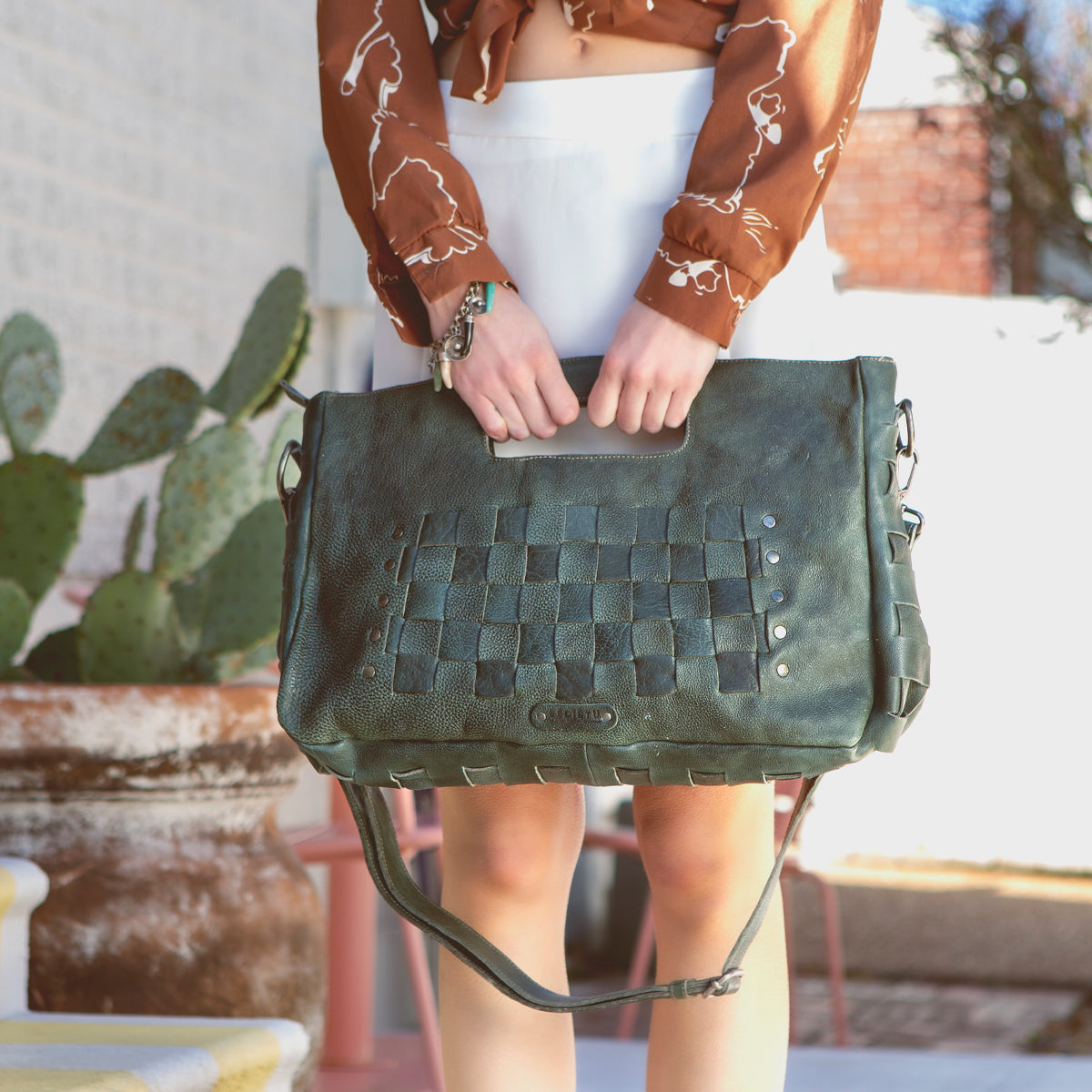 A woman is holding a Bed Stu Orchid L green leather bag.