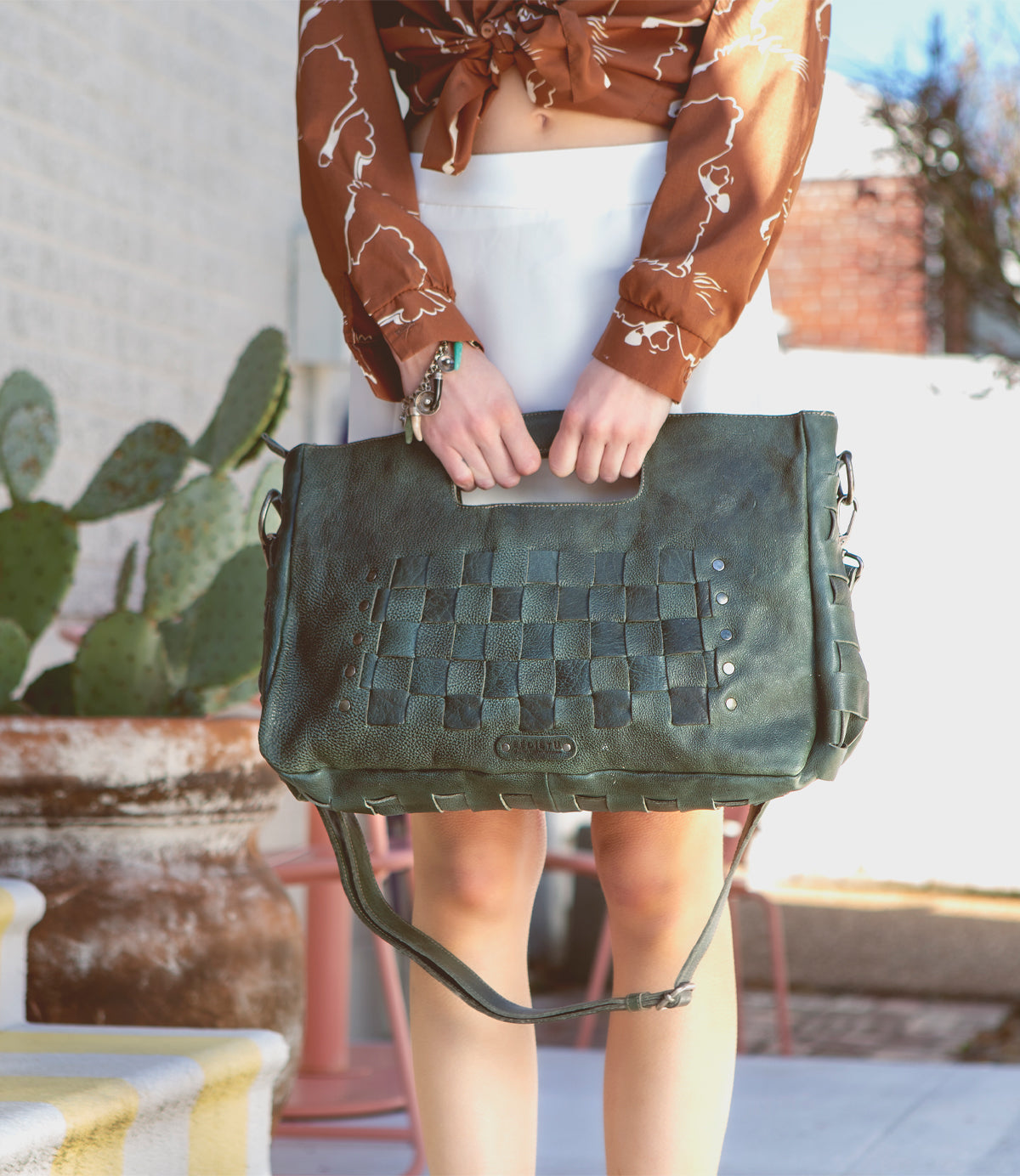 A woman is holding a Bed Stu Orchid L green leather bag.