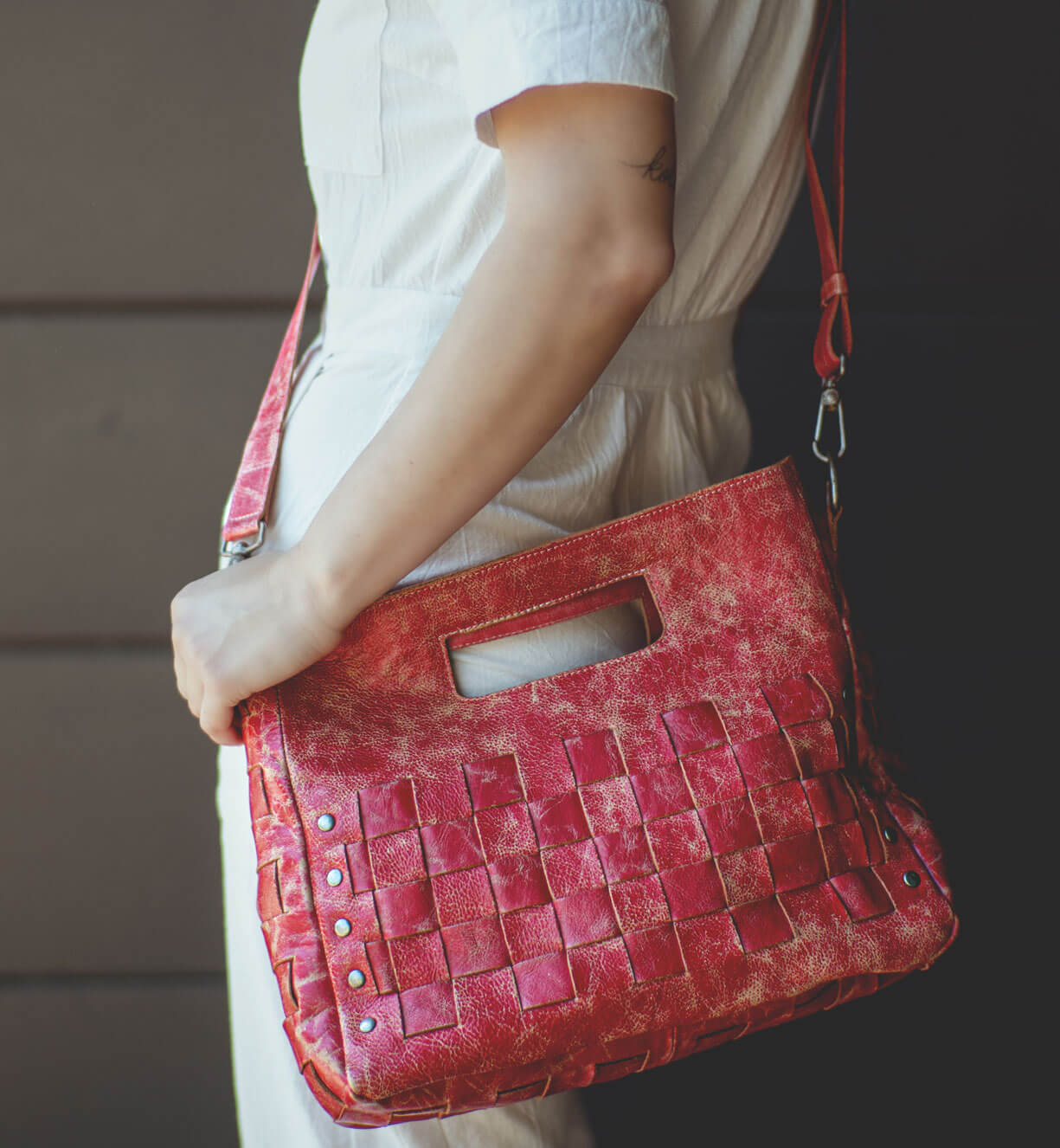 A woman is holding a red Orchid handbag by Bed Stu.