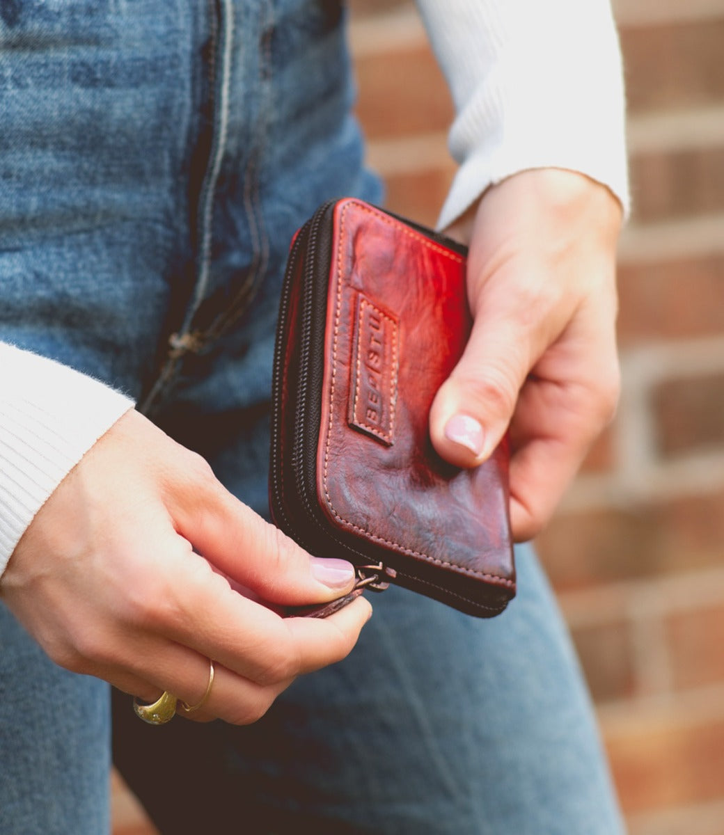 A woman holding a red leather Ozzie wallet by Bed Stu.