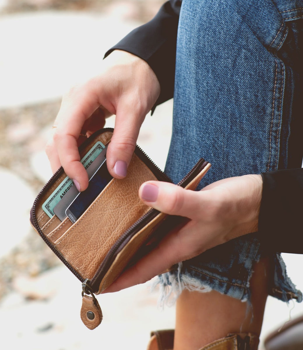 A woman is holding a Bed Stu Ozzie wallet in her hands.