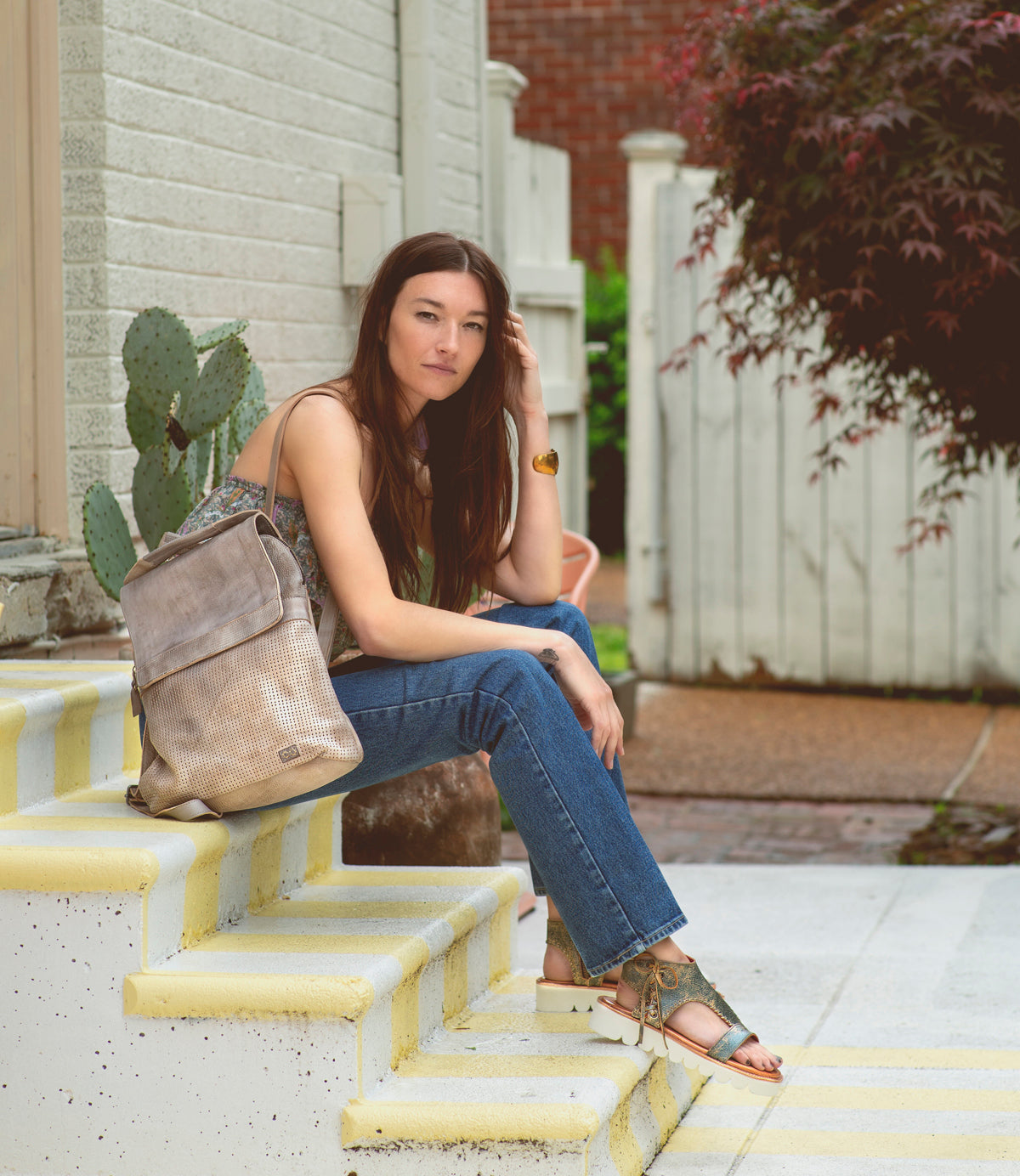 A woman sitting on the steps holding a Bed Stu Patsy bag.