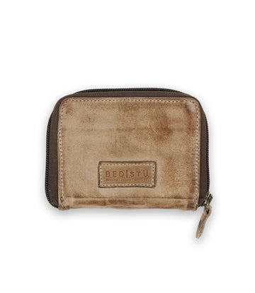 The Plus by Bed Stu is a brown leather wallet with a distressed texture and zipper closure. Featuring the BED|STÜ logo, it offers a compact design and multiple card slots, combining functionality with style.