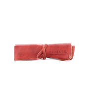 A rolled-up, brown leather wrap accessory organizer from Bed Stu with the brand name "Bed Stu" and the words "handmade, eco-friendly, footprint" stamped on it. Perfect for storing artist tools and called the Prepped Leather Wrap.