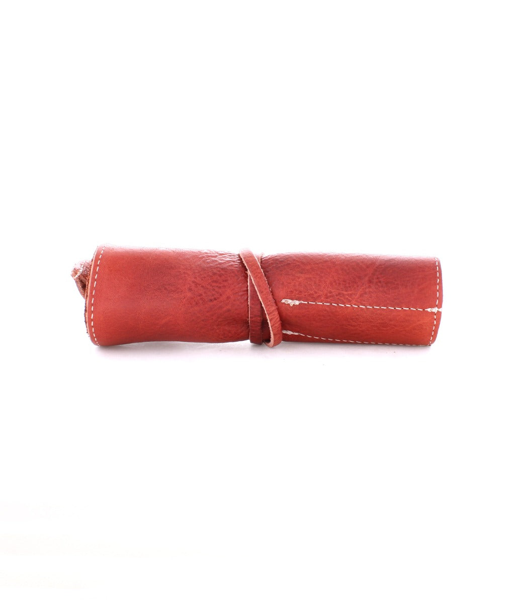 A rolled-up brown leather pouch secured with a leather strap, featuring visible stitching along the edges, perfect for storing artist tools. This exquisite piece, the Prepped Leather Wrap from Bed Stu, can be found at the Leather Shoppe.