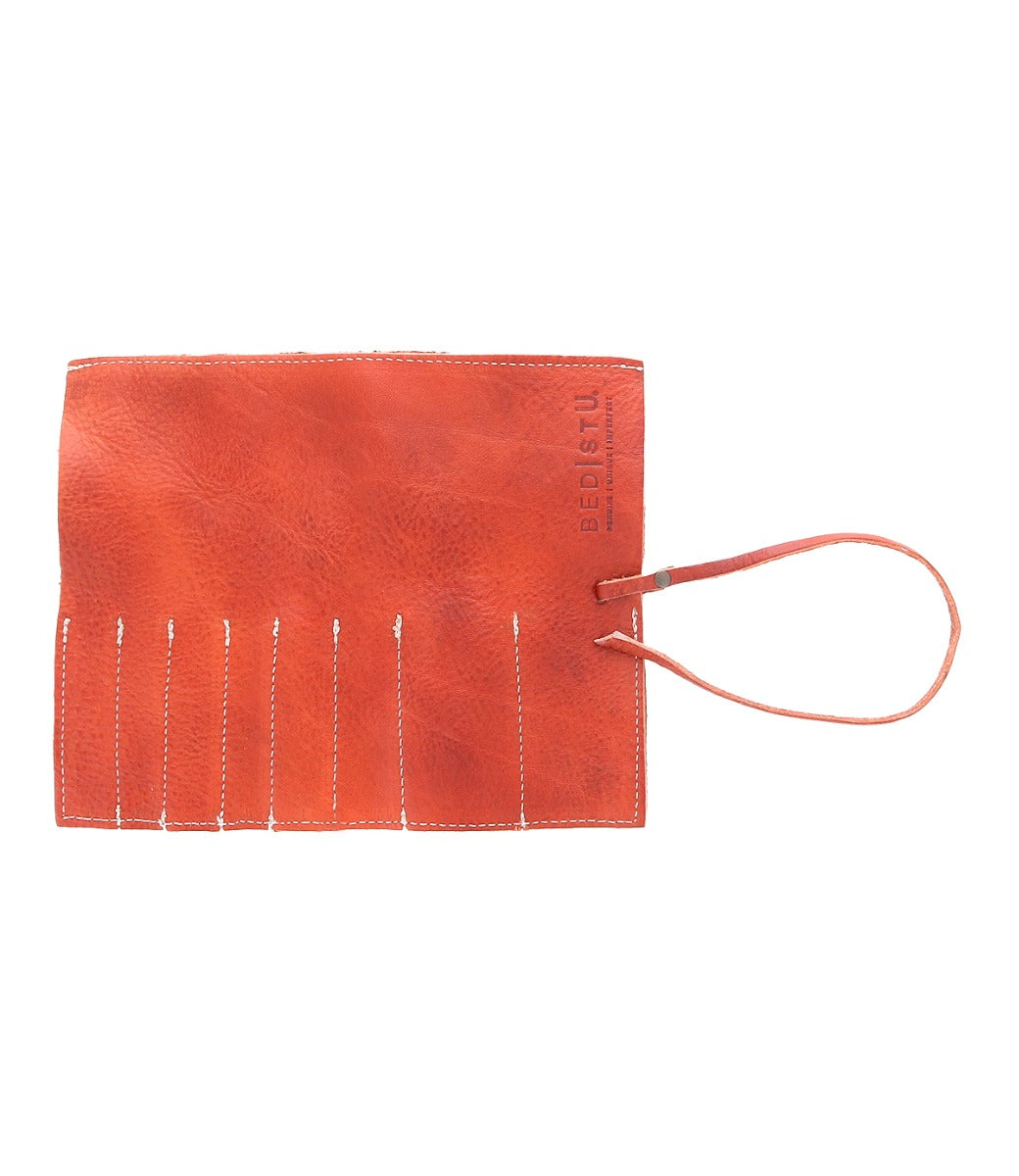 A flat, orange Bed Stu Prepped Leather Wrap with a strap and slots for storing artist tools.