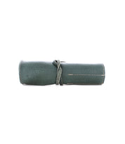 A rolled-up, green Prepped Leather Wrap tied with a matching leather strap from Bed Stu, featuring visible white stitching.